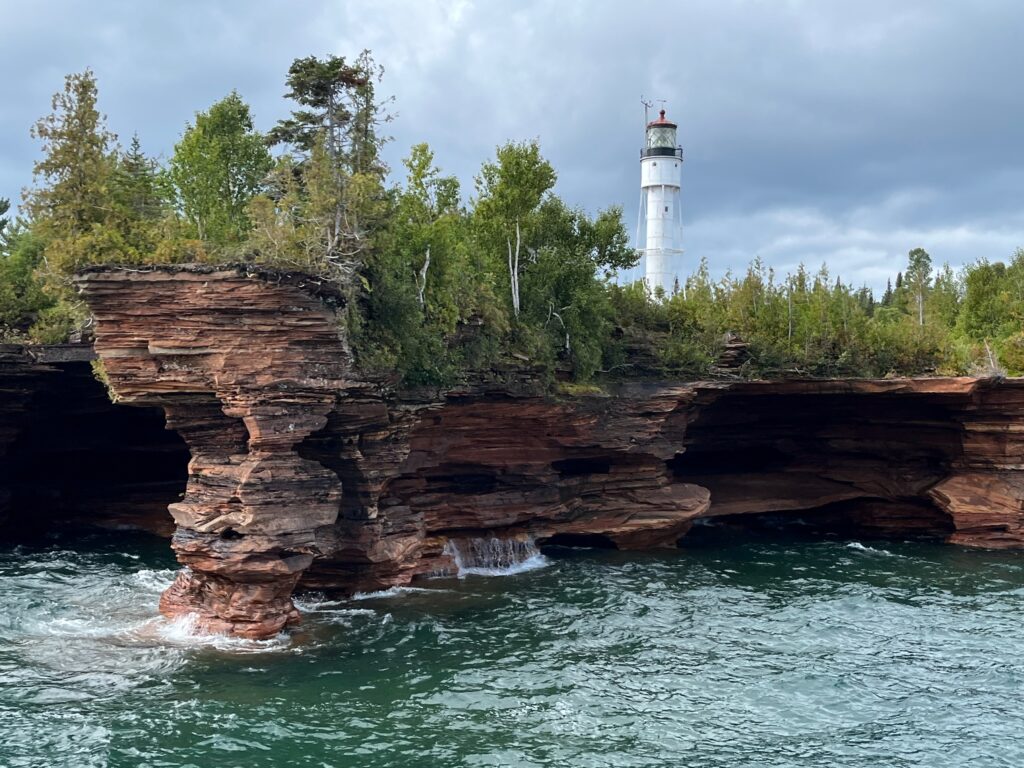 Devils Island Lighthouse behind some sea caves in Bayfield, WI