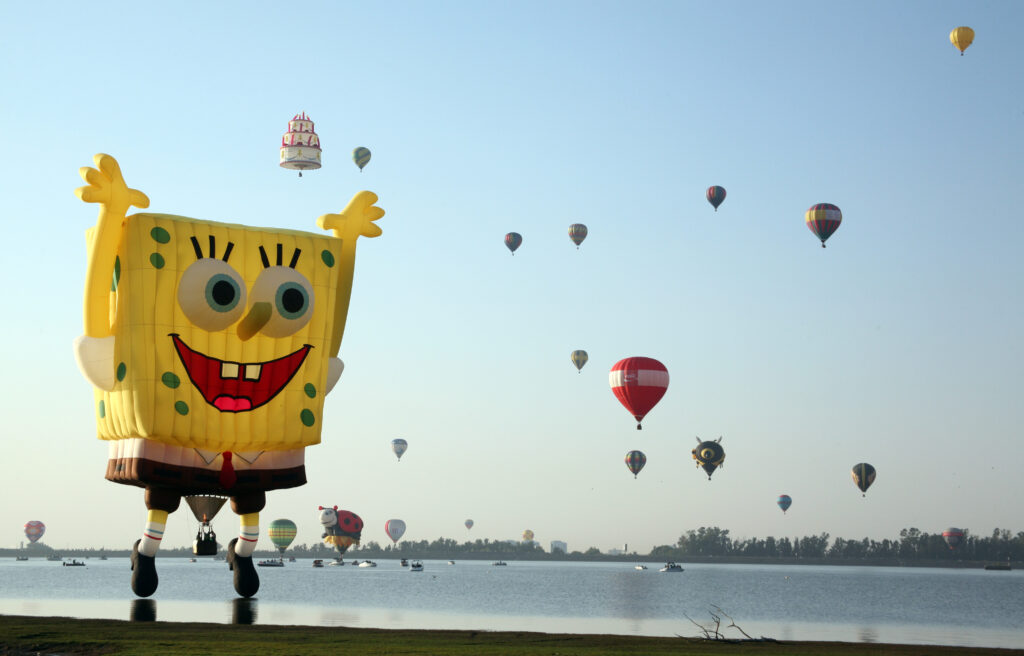 Several hot air balloons in flight including a Sponge Bob balloon.