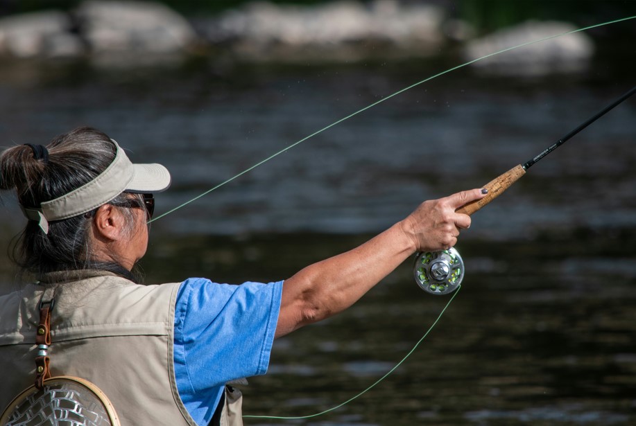 Woman casts a line into a creek in Wyoming.