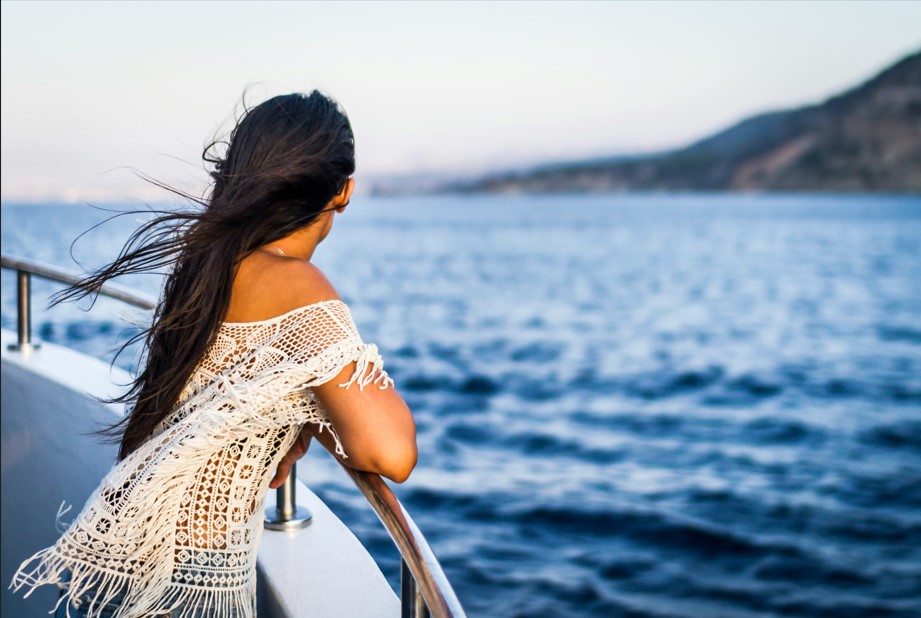 Woman enjoys the beautiful views of the coastline from her cruise ship.