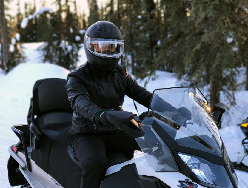 A rider enjoys the snowy landscape on his snowmobile.