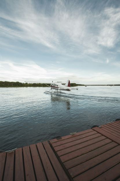 A sea plane takes off on the water, headed for one of the best Alaska fishing trips all inclusive.