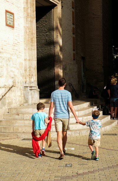 Father holds his two sons hands as they walk into church.