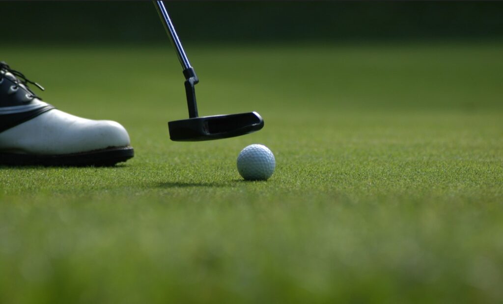Man lines up his putter with a golf ball at a golf course in Destin, Fl