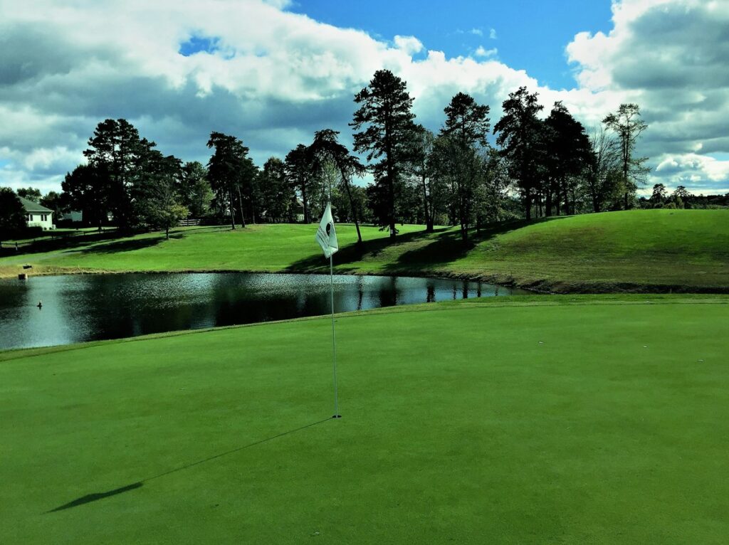 A white tee flag stands straight in a hole.