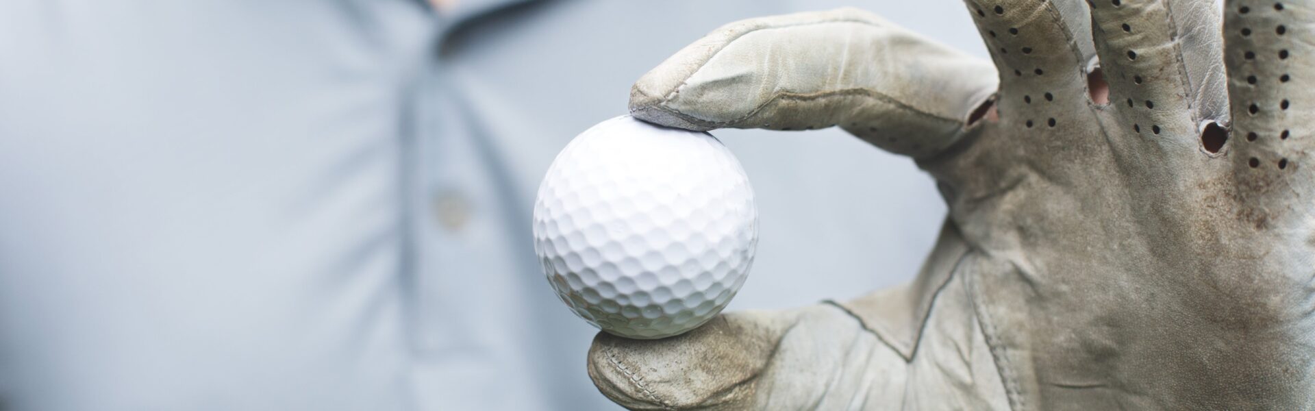 Golfer holds golf ball with his thumb and forefinger.