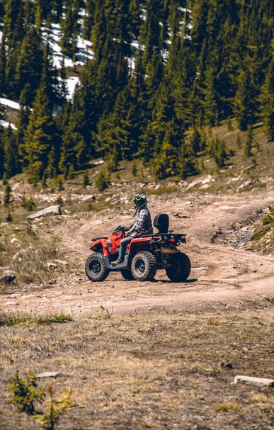 Man enjoys his ride on an ATV along a dirt road.