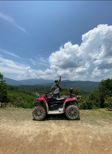 Woman holds her hand up high next to her ATV indicating her excitement for her Rocky Mountain National Park ATV adventure