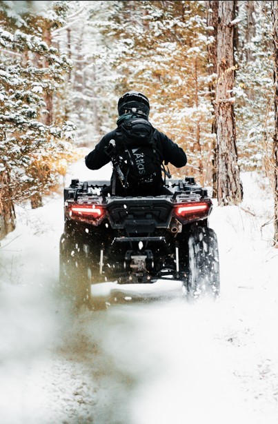 Winter rider drives an ATV down a snowy path.