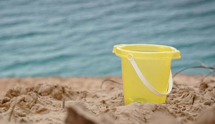 A yellow bucket sits in the sand