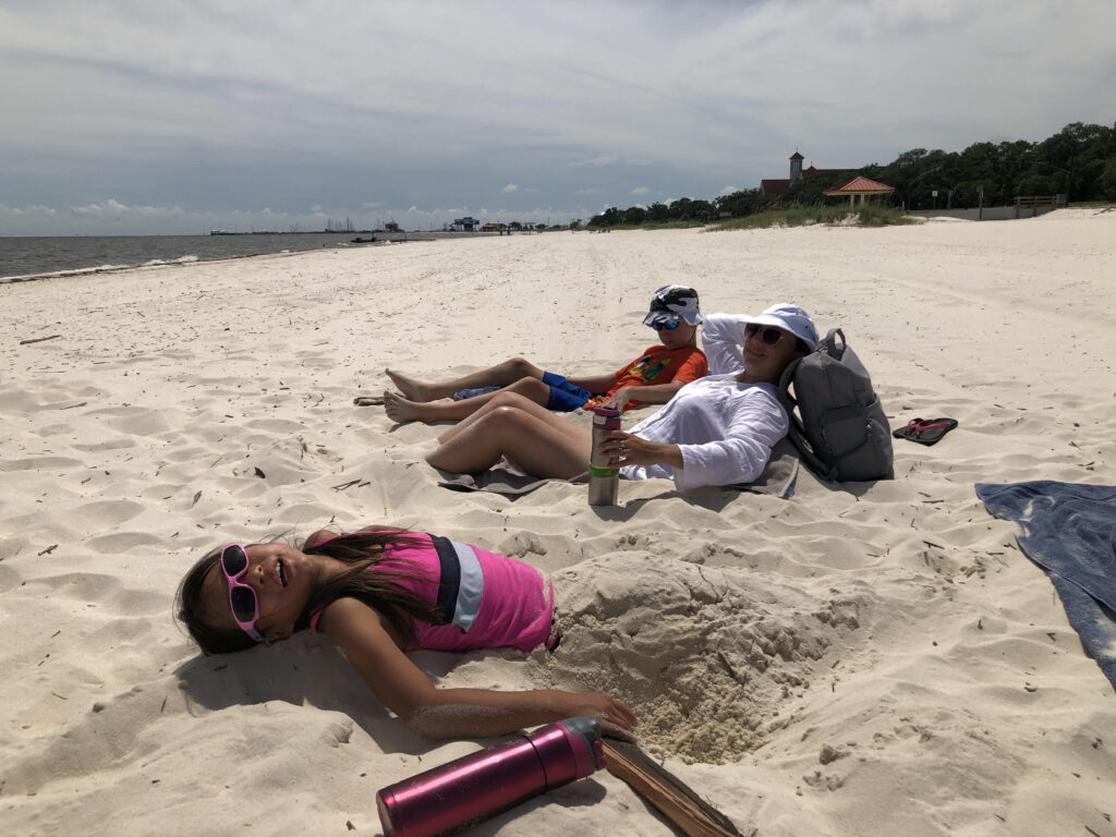Christine and her two youngest kids enjoy being partially buried in the sands of Long Beach, Mississippi. 