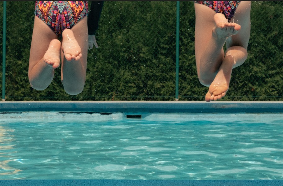 Rear view of two children springing into a pool. 
