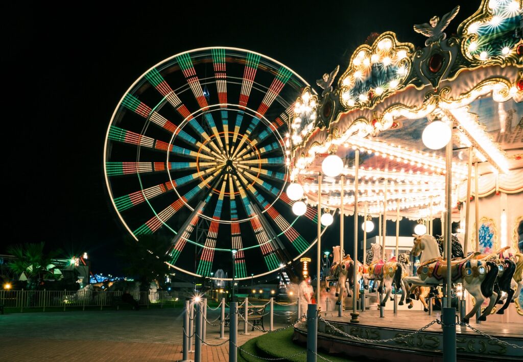 In the darkness of night, bright lights adorn a carousel and Ferris wheel near the water parks in Jersey City.