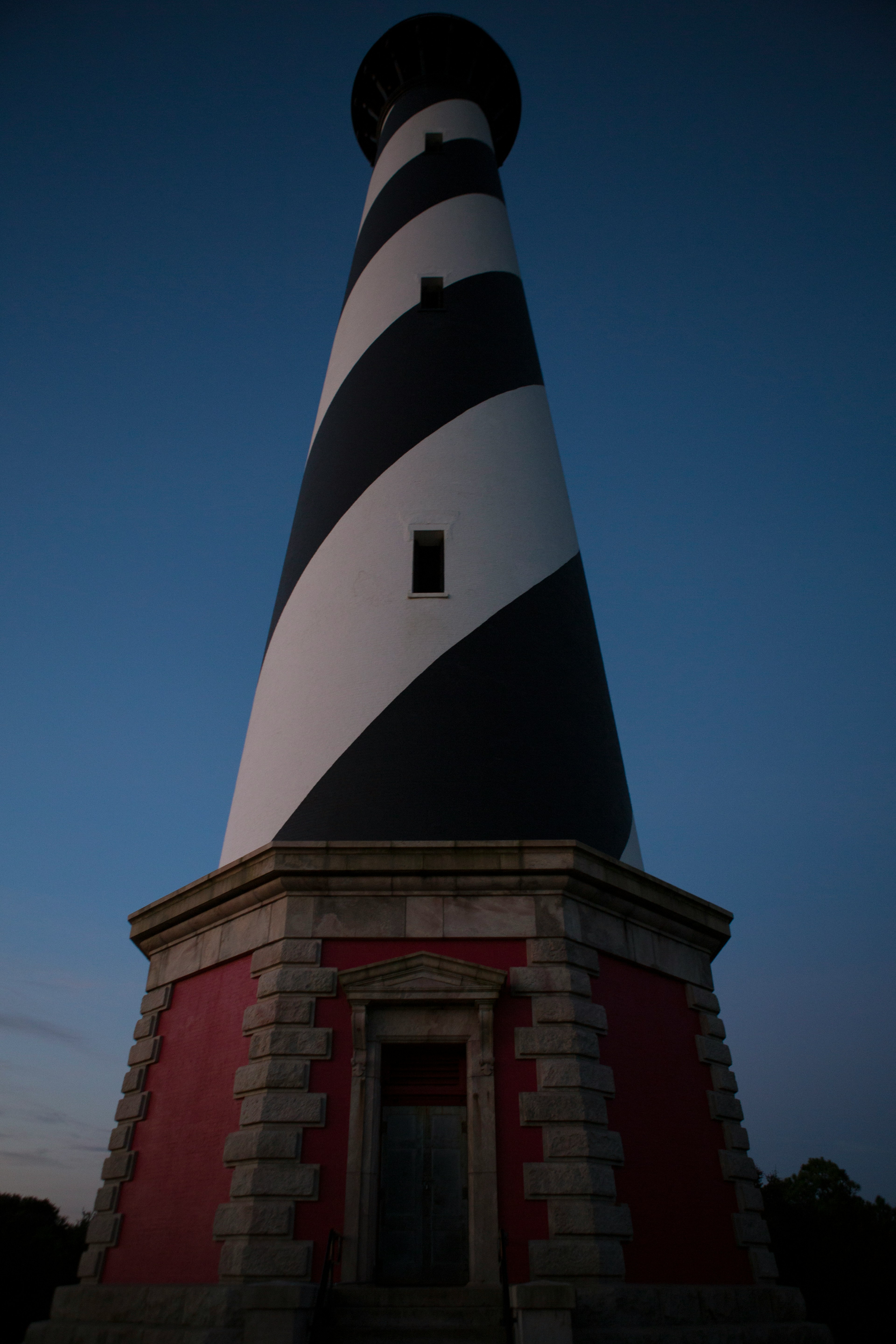 The lighthouse of Cape Hatteras stands proud against the bright blue sky. 
