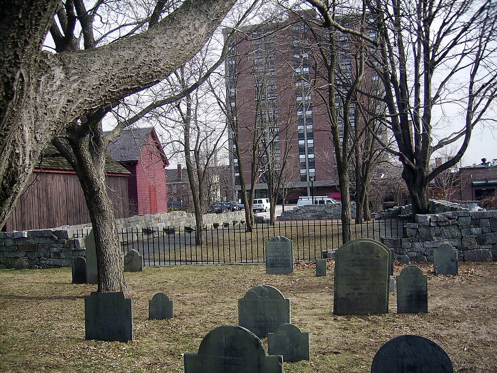 Historic grave markers surrounded by a black metal fence marks the territory known as the Old Burying Point Cemetery. 